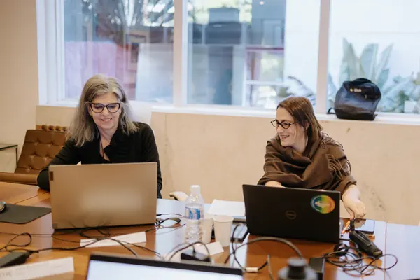 Duas participantes trabalham lado a lado nos notebooks